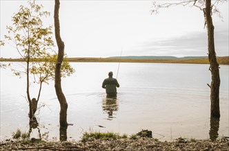 Sport fisherman fishing in lake on cloudy day, Cambara do sul, Rio Grande do sul, Brazil, South