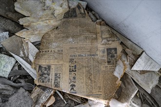 Remains of an old Kyrgyz newspaper with Cyrillic writing in an abandoned building, ghost town,
