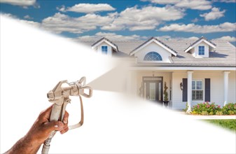 Professional spray painter holding spray gun spraying new house over white surface