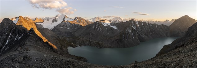 Panorama, Turquoise mountain lake Ala Kul Lake, Mountain peaks with glaciers glow red at sunset,