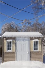 Storage shed facade and overhead electrical wires covered in thick ice and snow in residential