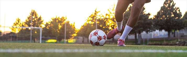 Player feet with the ball scoring a goal. Football player on the field running with the ball.