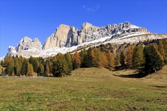 Massive rock formations above a grassland with autumnal trees, Italy, Alto Adige, Bolzano province,