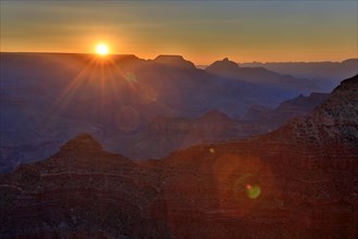 The first rays of the day illuminate the majestic rock faces of the Grand Canyon, Grand Canyon