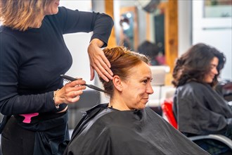 Side view and cropped photo of an unrecognizable hairdresser making an elegant bun for a client