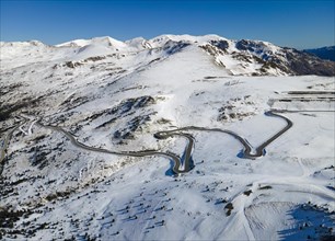 Aerial view of a winding mountain road through a wintry snowy landscape View from Grau Roig in the