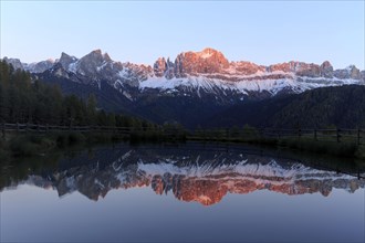 Early morning light illuminates a mountain range reflected in a still lake, Trentino-Alto Adige,