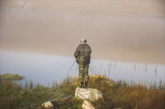 Sport fisherman fishing in lake on cloudy day, Cambara do sul, Rio Grande do sul, Brazil, South