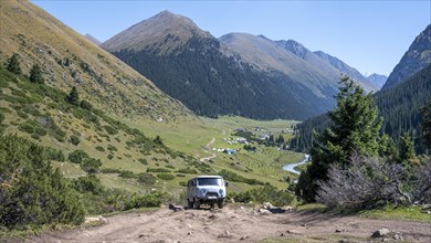 UAZ Buchanka, Russian off-road vehicle on 4x4 track, green mountain valley with village Altyn