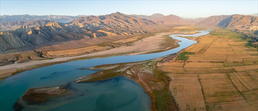 Naryn River between mountains and fields, at Toktogul Reservoir at sunset, aerial view, Kyrgyzstan,