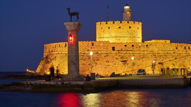 Night view of an old fortress with red lights and a sculpture by the sea, night shot, deer statue,