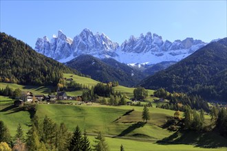Sunny view of an alpine village with green meadows and mountain panorama, Italy, Trentino-Alto