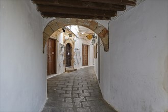 Narrow alley with arches, shops and cobbled floor in a traditional style, Lindos, Rhodes,