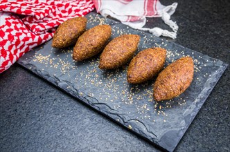 Delicious Lebanese (Arabic) food, kibbeh (kibe) on black slate stone and granite background with