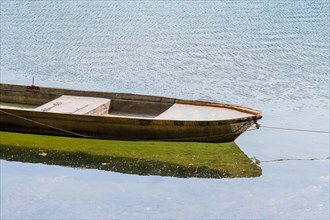 Small metal fishing boat floating in a river with its reflection in the water in South Korea