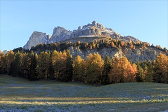 Autumn landscape with sunlit mountain peaks and colourful trees, Italy, Alto Adige, Bolzano