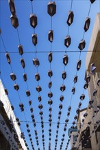 Rows of folded metal boat hats hanging from cables over an alley in the Old Port of Jaffa, Israel,