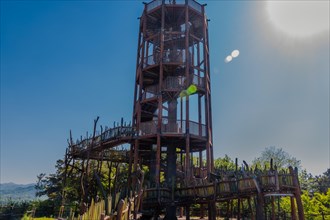 Wooden observation tower with winding staircase on top of mountain on sunny day with blue sky in