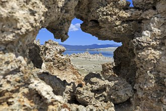View through a natural rock opening to a quiet landscape with blue sky in the background, Mono