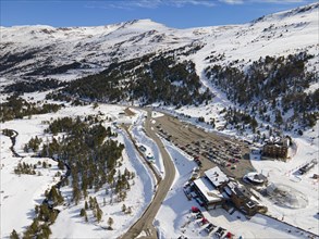 Aerial view of a snow-covered ski resort with car park and clear blue sky, Grau Roig, Encamp,