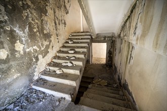 A crumbling staircase in an abandoned building with peeling paint and visible decay, ghost town,