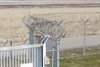 A security fence with barbed wire at an airport symbolises strict security precautions