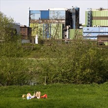 Couple lies on the Ruhrauen in front of the stainless steel plant in Witten, Ruhr area, North
