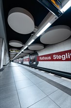 View along an empty underground platform with modern lights and advertising boards, Berlin, Rathaus