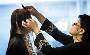 Valentyna Vysotska, hairdresser from Ukraine, combs her customer's hair, taken at the hairdressing