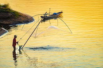 Fisherman with a sinking net at sunset on the Mekong, Luang Prabang, Laos, Asia