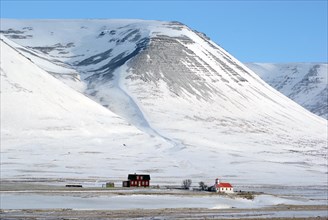 A single house and a small church in a lonely winter landscape