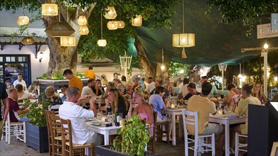 People dining in the evening in a cosy outdoor restaurant under lanterns, night shot, Rhodes Old