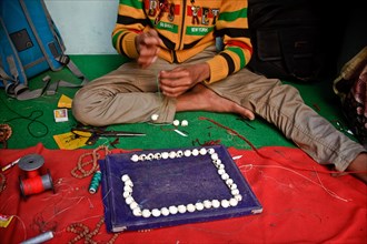Teenage boy making a necklace, Varanasi, India, Necklace intended to be sold to tourists, Asia