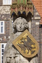 Head, sword and coat of arms of the Roland of Bremen in front of a brick facade in Bremen,