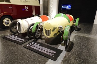 CUNO EIGENBAU, Two vintage racing cars in an exhibition, one in white and one in green, AUTOMUSEUM