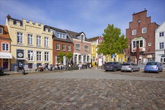 Restaurant and houses with colourful facades and a street of cobblestones in the harbour of Husum,