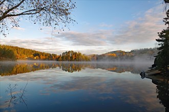 Sunrise and autumnal morning mist over a calm lake, foliage colouring, Bullaren, Bohuslaen. Sweden