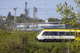 Regional train of the mobility brand bwegt unterwegs, railway embankment and overhead lines,