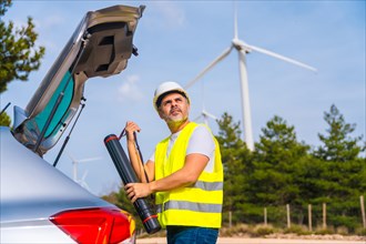 Profile photo of a male mature engineer carrying a drawing tube in a wind energy park