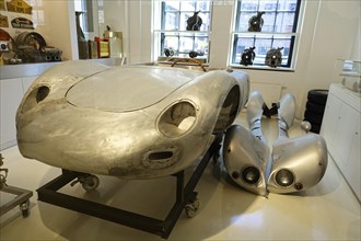 Partially dismantled vintage car in a car museum, showing metal bodywork and individual components,