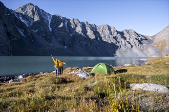 Two hikers camping in the wilderness, mountain lake in the Tien Shan, Lake Ala-Kul, Kyrgyzstan,