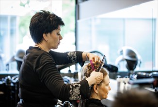 Valentyna Vysotska, hairdresser from Ukraine, puts up her customer's hair, photographed in the