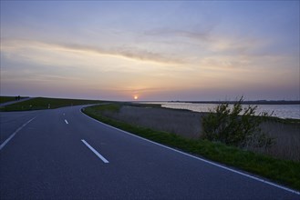 Reservoir South with country road L191 at sunset in Ockholm, district of Nordfriesland,