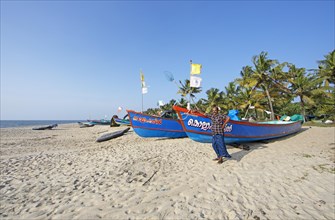 Indian fisherman, 42 years old, and colourful fishing boats at Marari Beach or beach, Mararikulam,