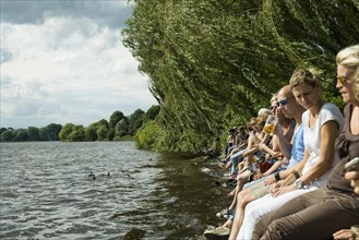 People sitting in the sun by the water, Summer, Outer Alster Lake, Hamburg, Northern Germany,