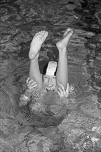 Boy looking through legs of another boy doing handstand, indoor swimming pool, Bamberg, Upper