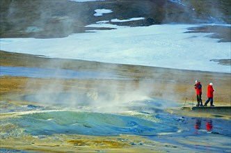 People standing in a winter landscape in front of a steaming mud spring, Namafjall, Myvatn,