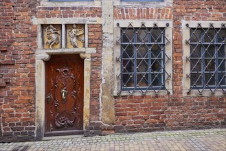 Relief in the lintel, old wooden door and barred windows of a house in Boettcherstrasse in Bremen,