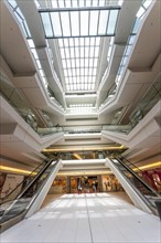 Interior view of a modern shopping centre with escalators and natural skylight, Berlin, Germany,