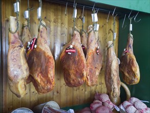 Ripe hams hanging in front of a wooden wall in a butcher's shop, Spain, Europe